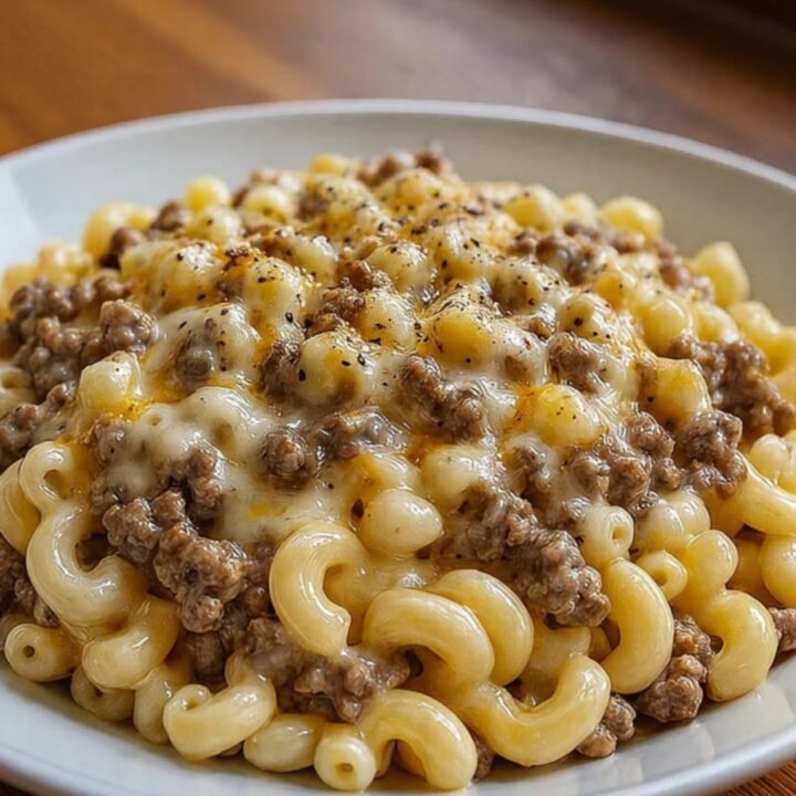 A close-up of creamy ranch beef macaroni with long, melted cheese strings being pulled up by a fork.