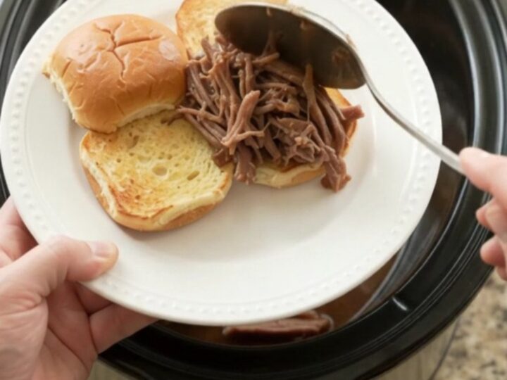 Shredded beef brisket in rich brown gravy with pearl onions in a slow cooker