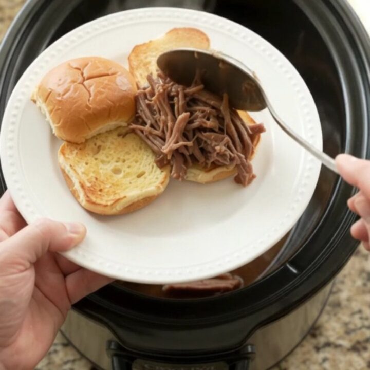 Shredded beef brisket in rich brown gravy with pearl onions in a slow cooker