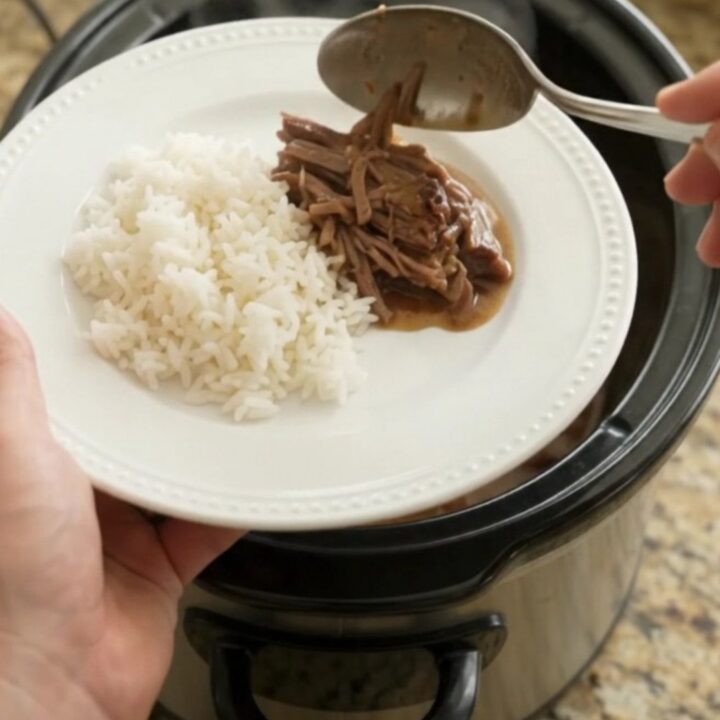 Shredded beef brisket with creamy Dijon gravy in a slow cooker, garnished with pearl onions