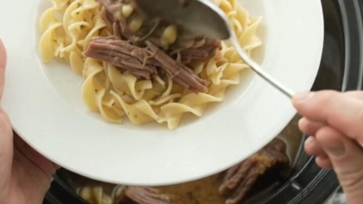 Slow-cooker Guinness brisket with pearl onions and garlic butter gravy in a black crock