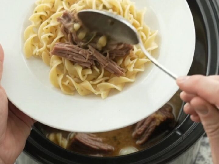 Slow-cooker Guinness brisket with pearl onions and garlic butter gravy in a black crock