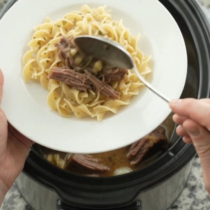 Slow-cooker Guinness brisket with pearl onions and garlic butter gravy in a black crock