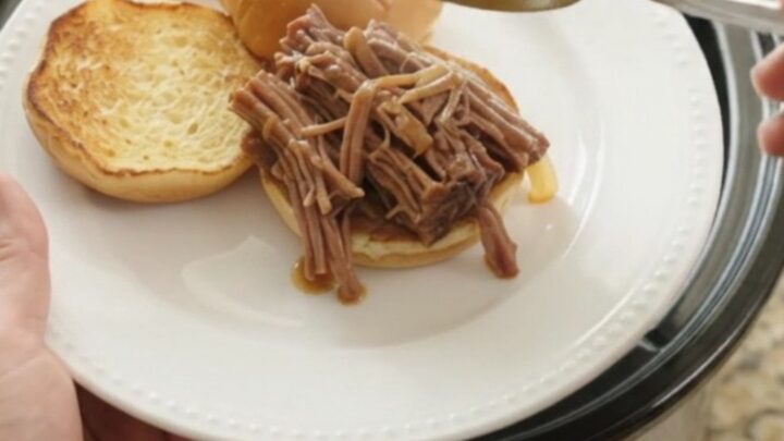 Shredded beef brisket with caramelized onions in a slow cooker, topped with gravy