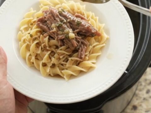 Shredded beef brisket in a slow cooker with garlic and herbs