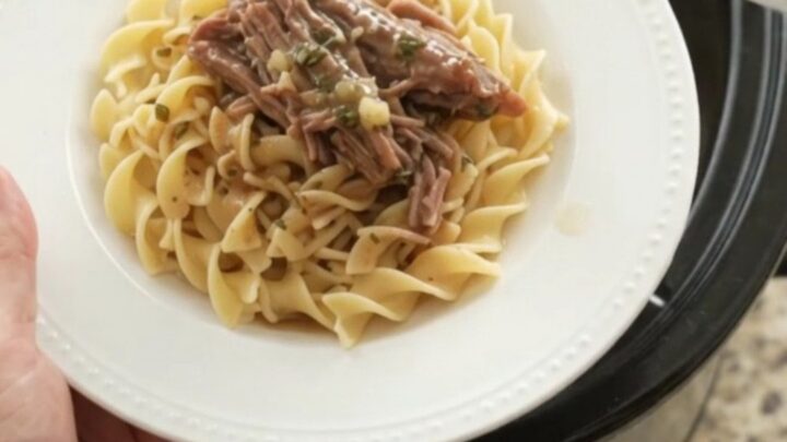 Shredded beef brisket in a slow cooker with garlic and herbs