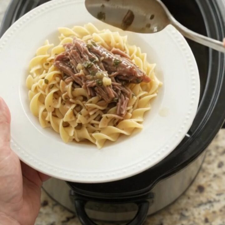 Shredded beef brisket in a slow cooker with garlic and herbs