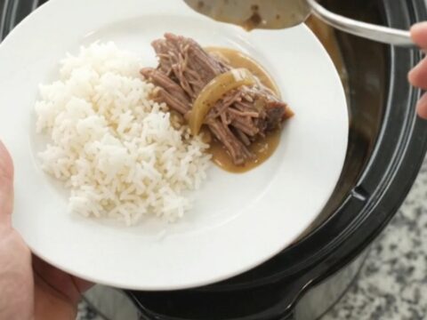 Slow-cooked beef brisket in creamy Dijon sauce with caramelized onions in a black crockpot
