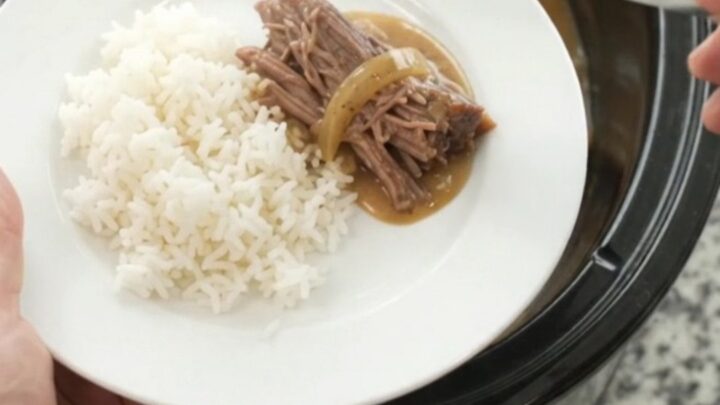 Slow-cooked beef brisket in creamy Dijon sauce with caramelized onions in a black crockpot