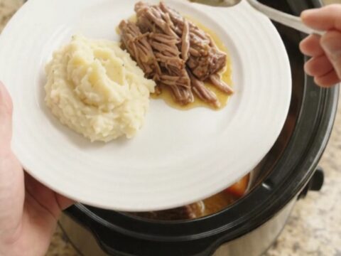 Slow-cooker beef brisket with shallots and carrots in a crockpot, topped with butter