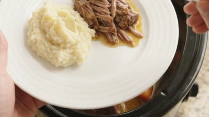 Slow-cooker beef brisket with shallots and carrots in a crockpot, topped with butter
