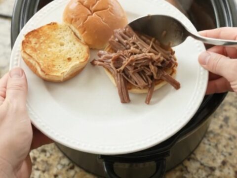 Slow-cooker beef brisket with shallots and carrots in rich gravy, served on a plate