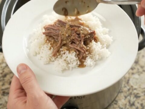 Slow cooker brisket with creamy Dijon sauce, shallots, and carrots in a black crockpot