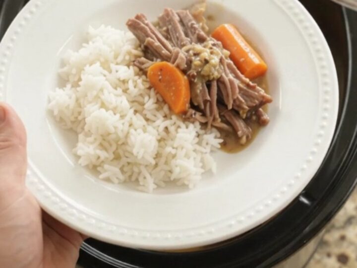 Slow-cooker brisket with potatoes and carrots in creamy Dijon gravy, in a black ceramic pot