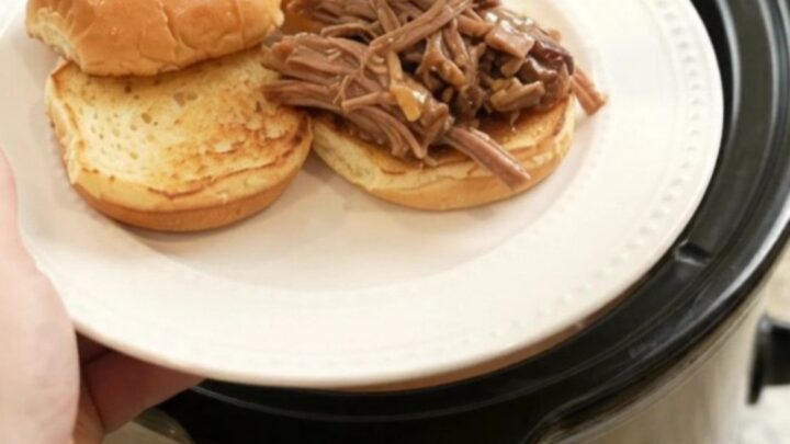 Slow-cooked beef brisket with portobello mushrooms in rich brown gravy, served in a black ceramic slow cooker.