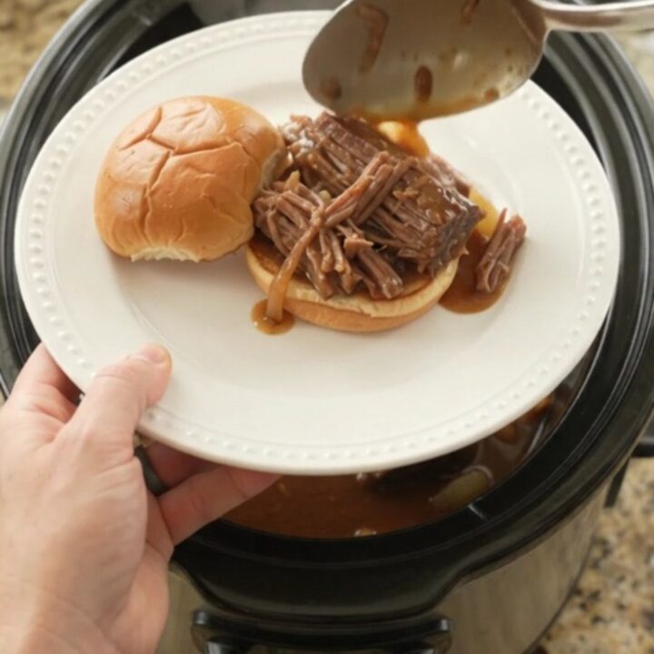 Slow cooker beef brisket with sweet peppers and onions in rich brown gravy, ready to serve