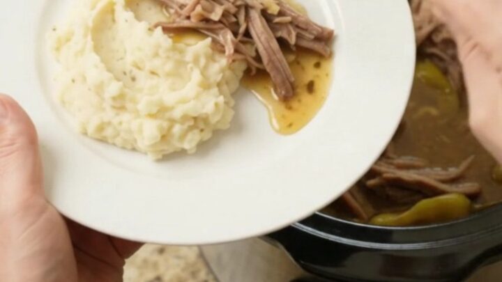 Slow cooker pork shoulder with pepperoncini and butter in a black ceramic crock
