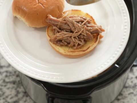 Shredded pork shoulder in a slow cooker with pepperoncini and brown gravy
