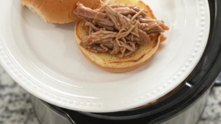 Shredded pork shoulder in a slow cooker with pepperoncini and brown gravy