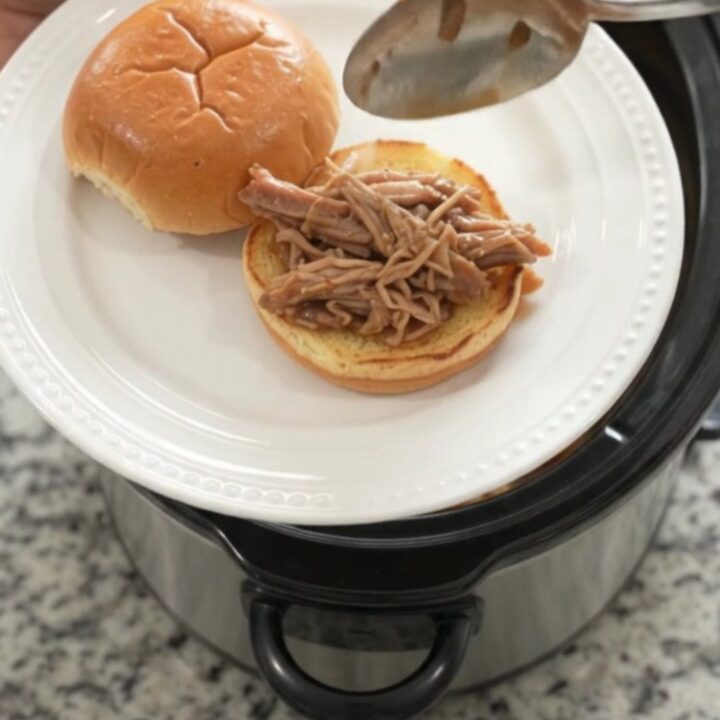 Shredded pork shoulder in a slow cooker with pepperoncini and brown gravy
