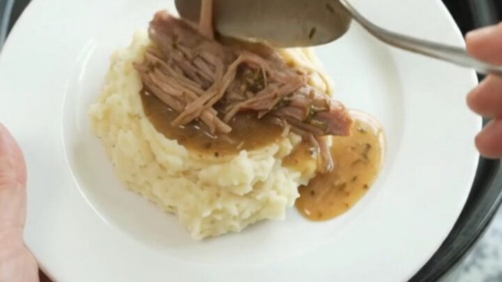 Shredded pork shoulder in a slow cooker with buttery jus