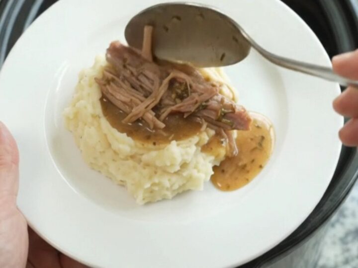 Shredded pork shoulder in a slow cooker with buttery jus
