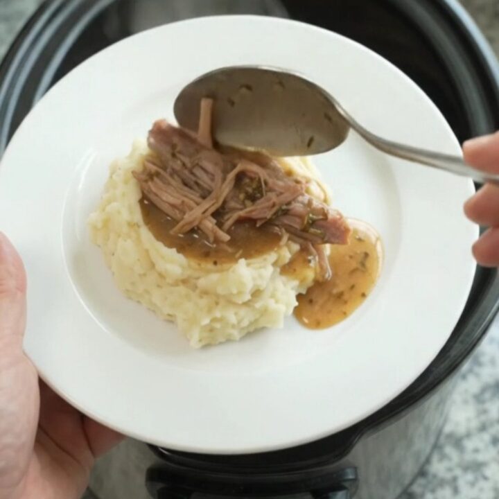 Shredded pork shoulder in a slow cooker with buttery jus