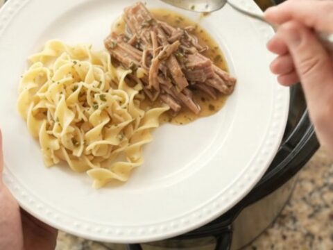 Shredded pork shoulder with mushrooms and garlic butter gravy in a black slow cooker