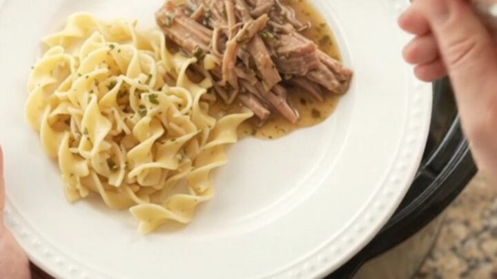 Shredded pork shoulder with mushrooms and garlic butter gravy in a black slow cooker