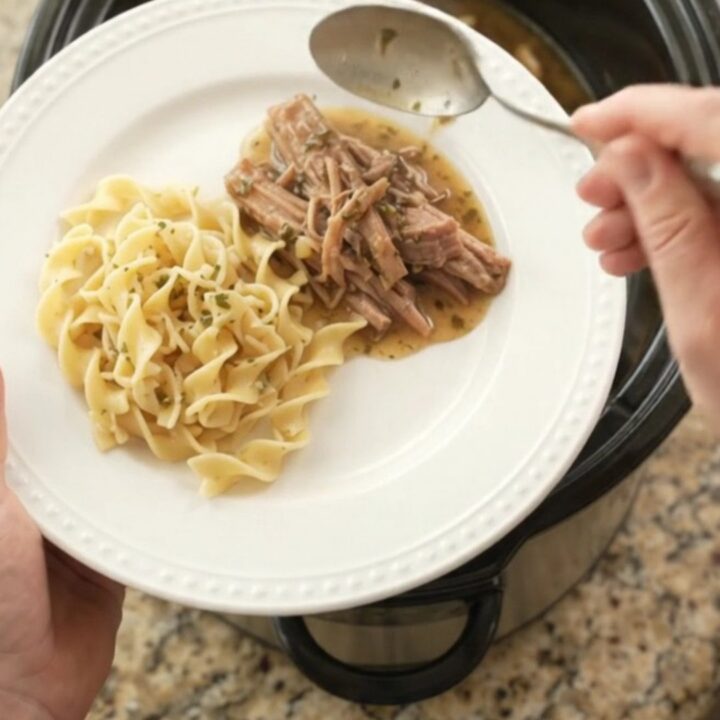 Shredded pork shoulder with mushrooms and garlic butter gravy in a black slow cooker