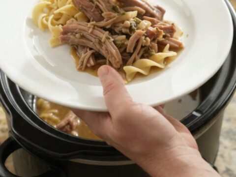 Slow-cooked pork shoulder with caramelized onions and garlic butter gravy in a black crockpot
