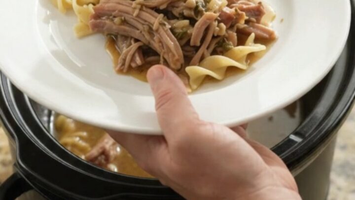 Slow-cooked pork shoulder with caramelized onions and garlic butter gravy in a black crockpot