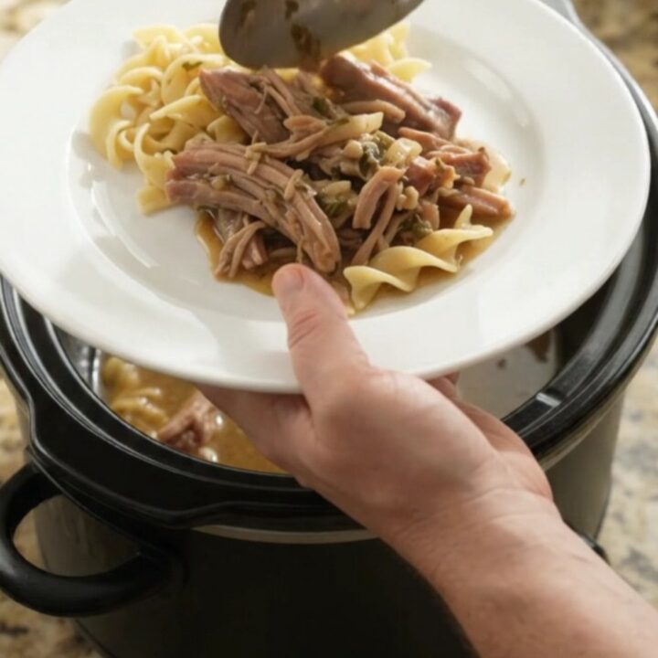 Slow-cooked pork shoulder with caramelized onions and garlic butter gravy in a black crockpot