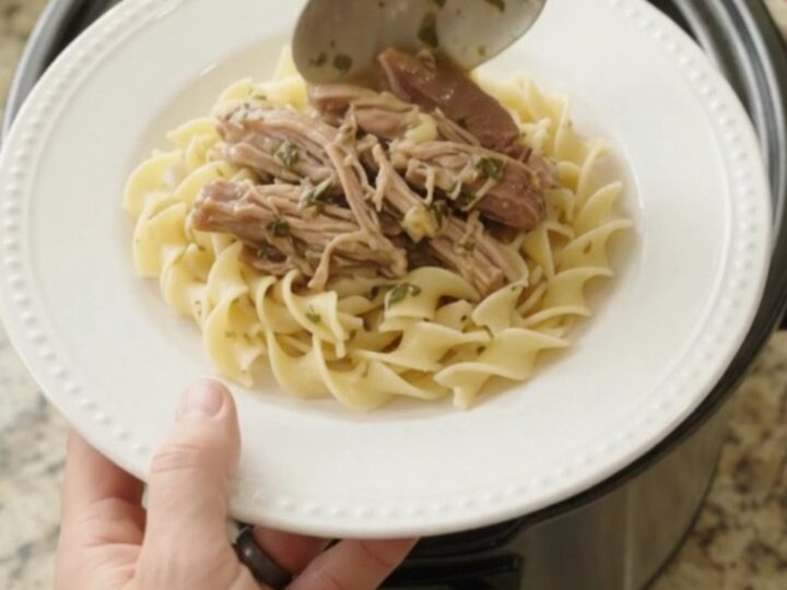 Slow-cooked pork shoulder with garlic and herbs in a black crockpot