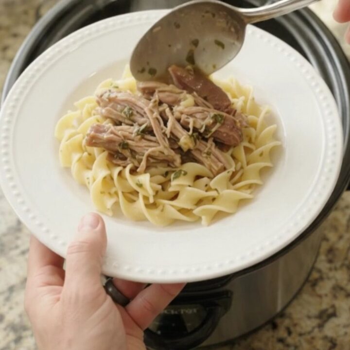Slow-cooked pork shoulder with garlic and herbs in a black crockpot