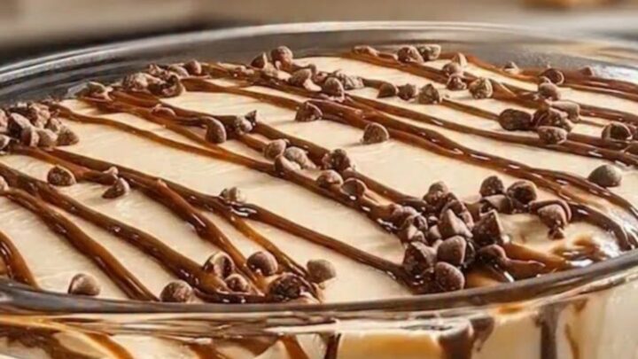 A clear glass bowl filled with layers of dark chocolate cookie crumbs and creamy dulce de leche mousse.