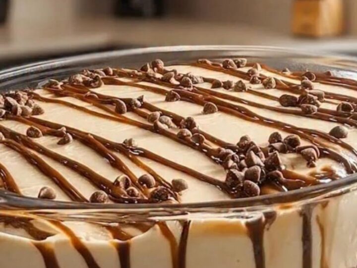 A clear glass bowl filled with layers of dark chocolate cookie crumbs and creamy dulce de leche mousse.