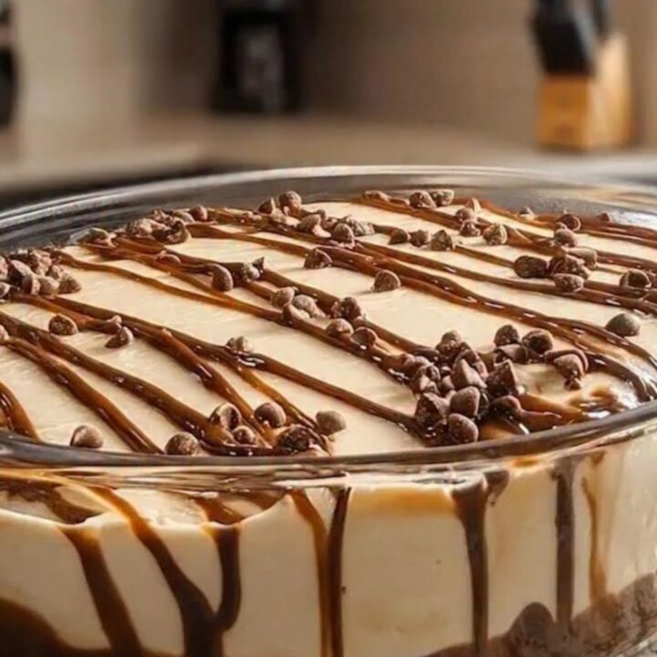A clear glass bowl filled with layers of dark chocolate cookie crumbs and creamy dulce de leche mousse.