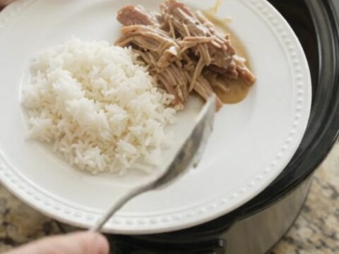 Slow cooker pork shoulder with creamy Dijon sauce, garlic, and fresh herbs in a black crockpot