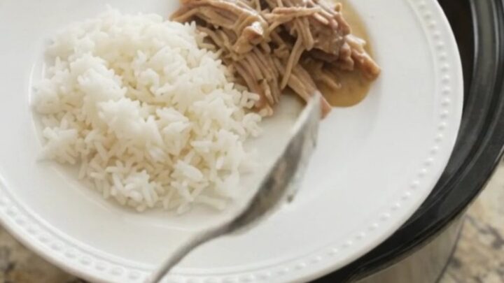Slow cooker pork shoulder with creamy Dijon sauce, garlic, and fresh herbs in a black crockpot