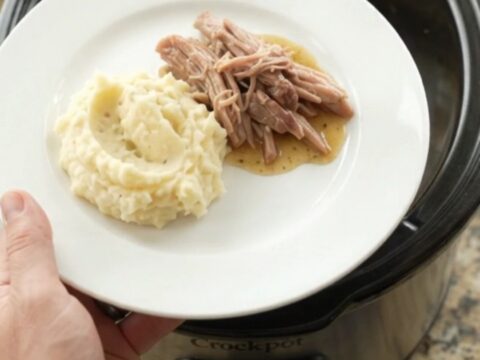 Slow cooker pork shoulder with rosemary and thyme, shredded and glistening in butter sauce