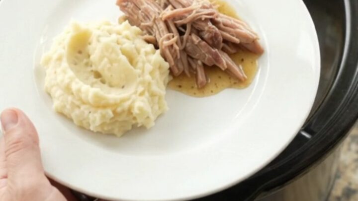 Slow cooker pork shoulder with rosemary and thyme, shredded and glistening in butter sauce