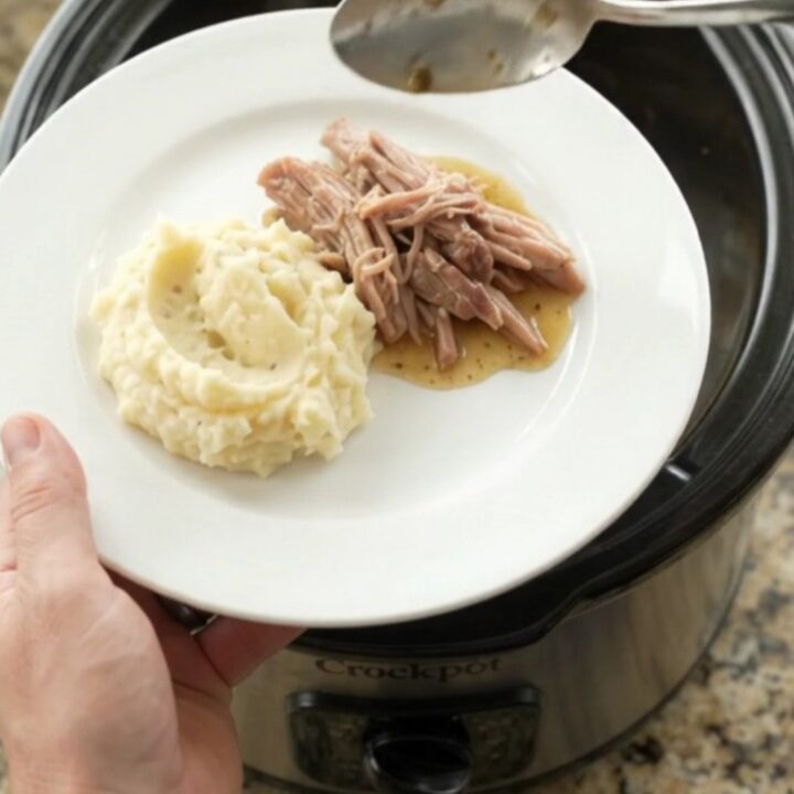 Slow cooker pork shoulder with rosemary and thyme, shredded and glistening in butter sauce