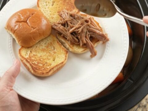 Slow-cooker pork shoulder with shallots and carrots in rich brown gravy, ready to serve
