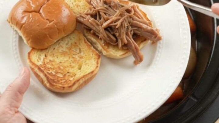 Slow-cooker pork shoulder with shallots and carrots in rich brown gravy, ready to serve
