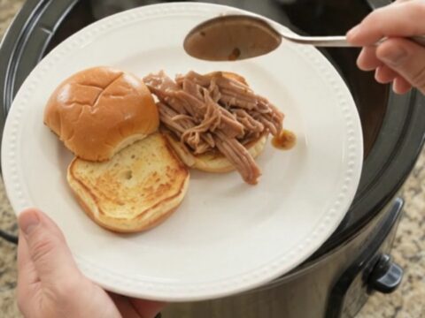 Slow-cooker pork shoulder with Yukon Gold potatoes and carrots in rich brown gravy, served in a black crockpot.