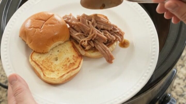 Slow-cooker pork shoulder with Yukon Gold potatoes and carrots in rich brown gravy, served in a black crockpot.