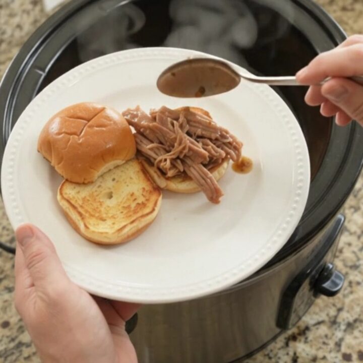 Slow-cooker pork shoulder with Yukon Gold potatoes and carrots in rich brown gravy, served in a black crockpot.