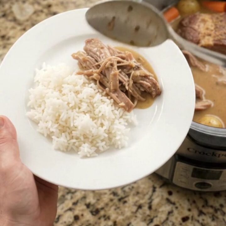 Slow-cooker pork shoulder with Dijon cream gravy, potatoes, and carrots in a black crockpot