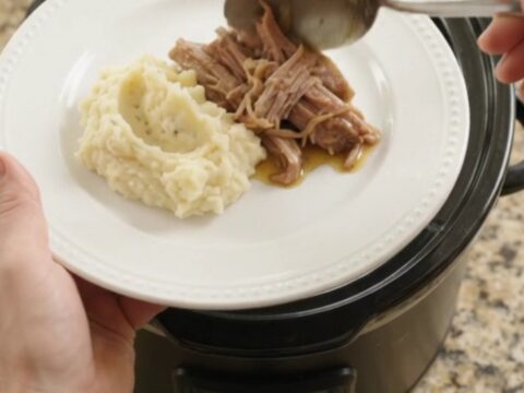 Pulled pork shoulder with portobello mushrooms in a slow cooker, topped with butter